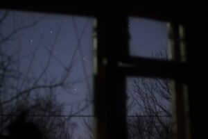 Homeowner relaxing on a backyard deck under the stars, gazing at the night sky.