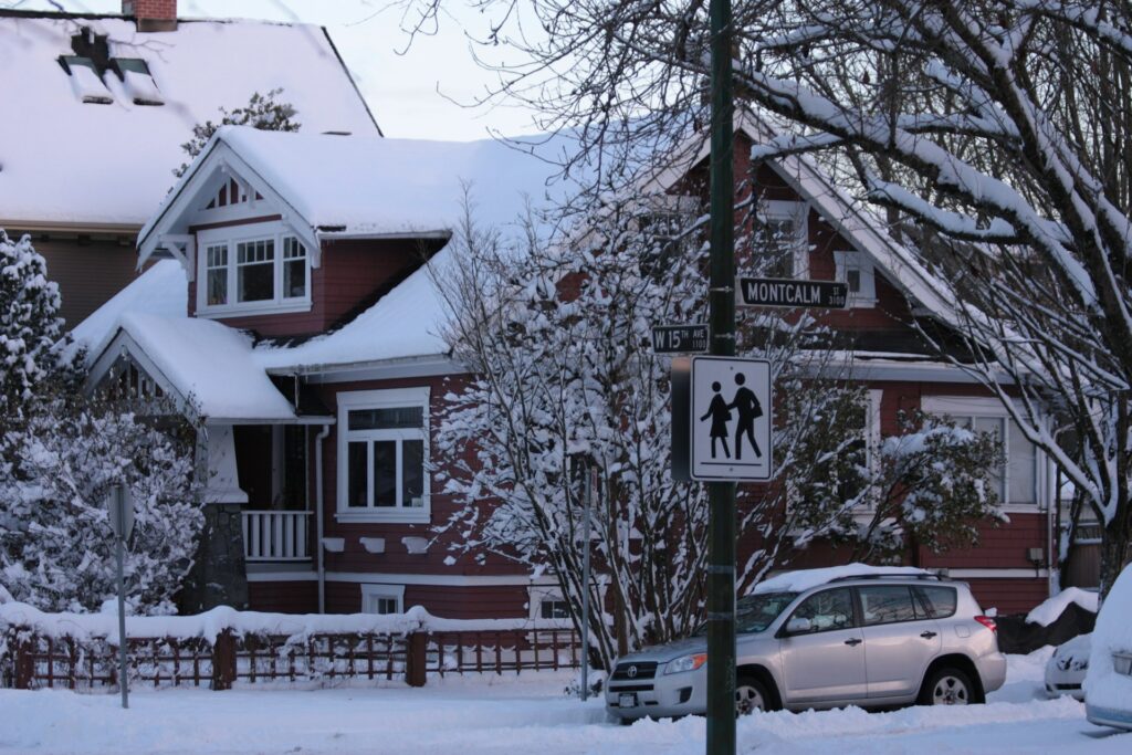 A professional roofing contractor inspects wind-damaged shingles on a Vancouver, Washington home with the Columbia Gorge in the background, preparing the roof for winter storms and heavy rain between November and March.