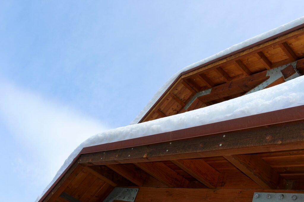 Professional roofing contractor inspecting residential roof in snowy Bend Oregon with Cascade Mountains in background