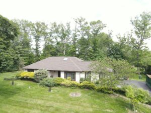 Vancouver Washington homeowner reviewing tax refund documents while planning roof replacement project with new shingles visible