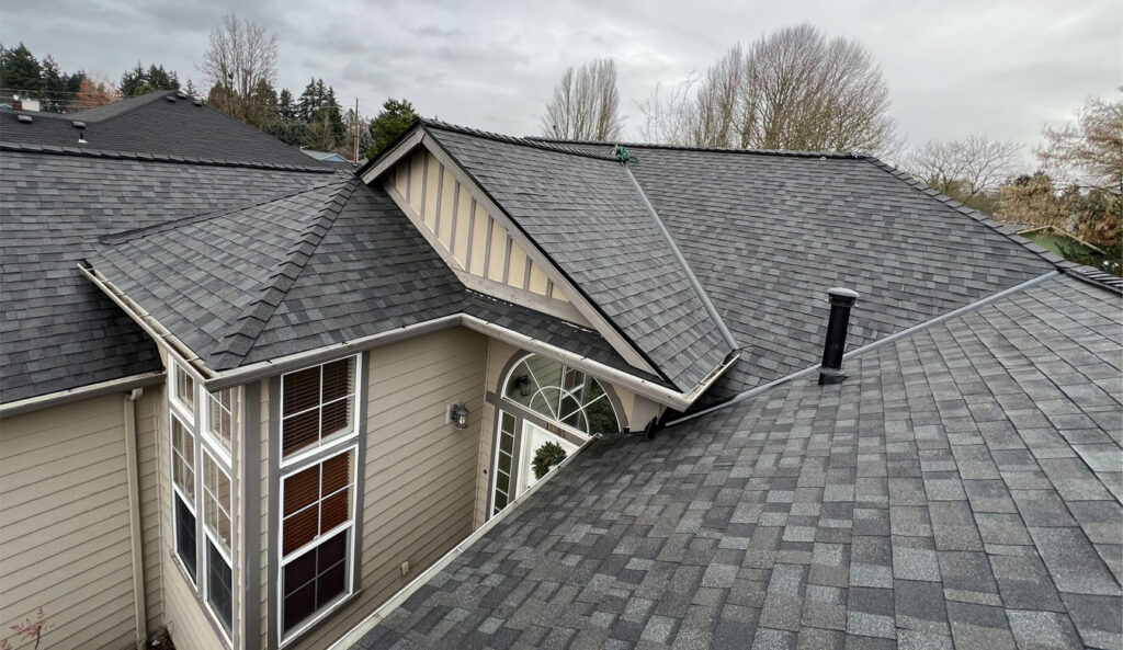 Roofing contractor inspecting moss-covered roof and gutters on a Vancouver Washington home in spring