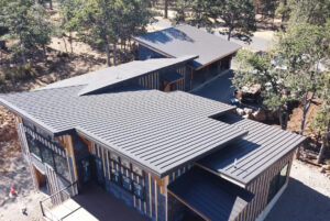 Standing seam metal roof installed by HOMEMASTERS on a Portland SW Oregon home surrounded by fir trees