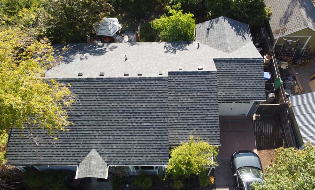 Overhead view of a new dark architectural shingle roof on a single story home, coastal roof replacement for Gold Beach