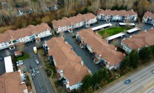 Drone view of a multi-building residential community with matching shingle roofs, HOA roof replacement for Happy Valley