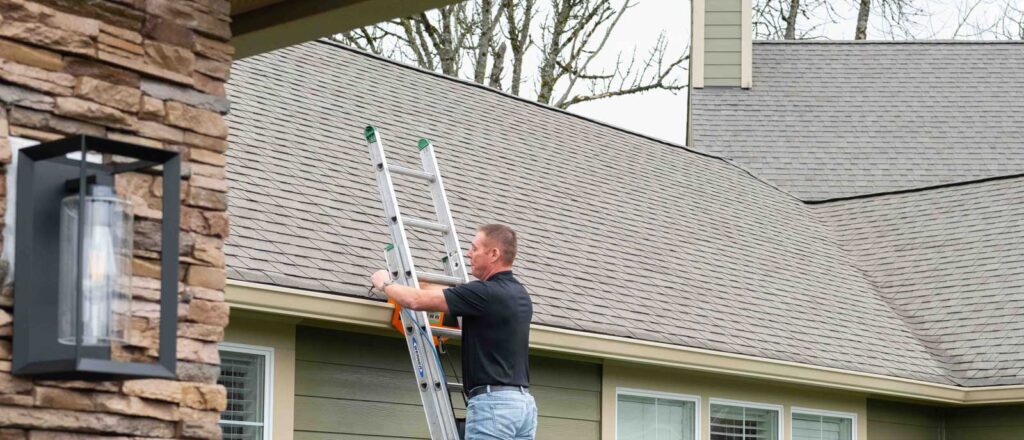 Roofer inspecting asphalt shingles and flashing on a home, roof inspection by HOMEMASTERS Vancouver for Hazel Dell