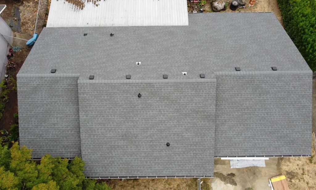 Overhead view of a new gray shingle roof with box vents and gutters, roof replacement cost guide for Klamath Falls